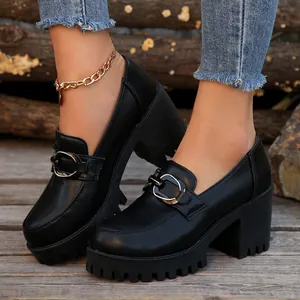 Detail van zwarte loafers met blokhak, metalen gesp en dikke platformzool voor dames