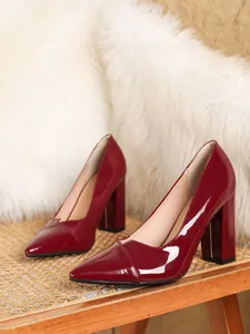 Elegante weinrote Lackleder-Pumps mit Blockabsatz auf einem klassischen Korbstuhl