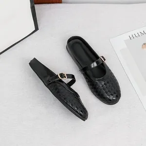 Macro view of elegant black woven mules featuring a round toe and Mary Jane buckle strap