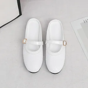 Detailed view of white woven flat mule shoes with elegant gold-tone buckle strap and round toe