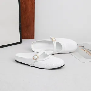 Detailed macro view of white woven flat mules featuring an elegant gold buckle strap