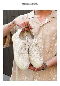 Close-up view of men's hand-woven low-top cream casual sneakers held by a model.