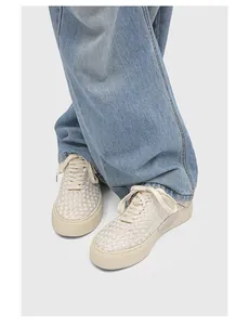 Detailed view of handmade woven cream low-top sneakers with durable vulcanized soles.