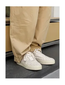 Detail view of the intricate hand-woven texture on cream low-top men's casual sneakers