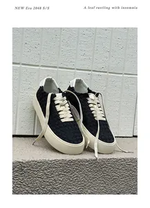 Detailed view of black handmade woven low-top sneakers with beige thick rubber soles