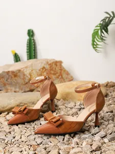 Detail of brown pointed-toe high heels with elegant bow and crocodile texture.