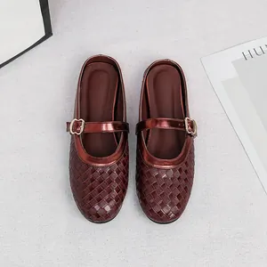 Close-up of woven burgundy flat mules with decorative buckle strap