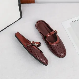 Close-up of wine red woven leather flat mules with elegant gold buckle strap