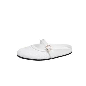 Detail view of a white woven mule slipper with an elegant gold buckle strap design.