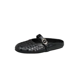 Close-up of black women's closed-toe mules featuring woven texture and buckle strap.