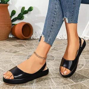Primer plano de sandalias negras con plataforma y punta abierta con jeans de mezclilla.