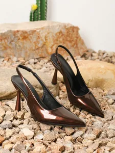 Close-up van elegante bruine lakslingback-pumps op een natuurlijke rotsachtige bodem.