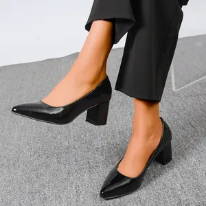 Detail shot of black patent leather chunky heel pumps with pointed toe design.