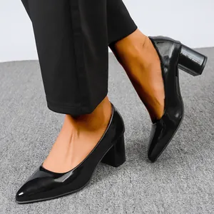 Close-up view of black patent leather pumps with block heels and pointed toes