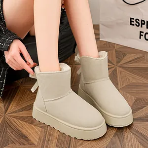 Dettaglio di stivali da neve beige con suola spessa e fiocco decorativo sul retro.