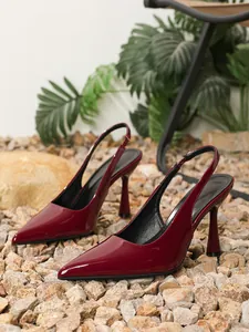 Detailopname van elegante bordeauxrode lakleren slingbacks op natuurstenen