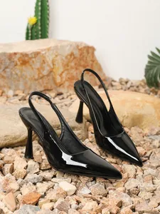 Detailweergave van elegante zwarte lakleren slingback hakken op een rotsachtige achtergrond