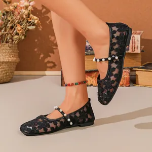 Detalle de bailarinas de malla de encaje floral negro con elegante tira de perlas en el pie