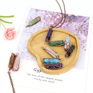 Assorted handmade wire wrapped tree of life natural hexagonal stone pendants on a tray.