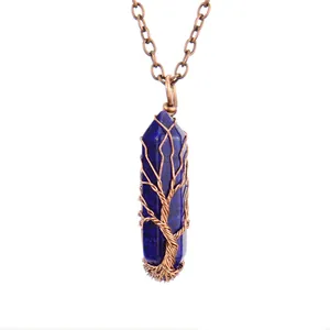 Close-up of handmade wire-wrapped Tree of Life pendant on blue crystal column.