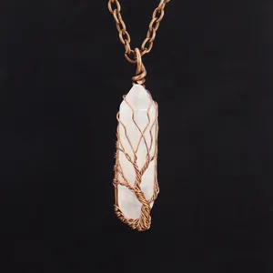 Close-up detail of a handmade copper wire wrapped tree of life pendant on a white crystal