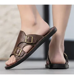 Close-up side view of stylish brown leather slides featuring double gold buckles on feet
