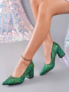 Primer plano de elegantes zapatos de salón verdes con purpurina y tacón de bloque