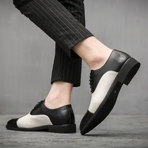 Vista dettagliata di eleganti scarpe stringate bicolore uomo indossate con pantaloni gessati.