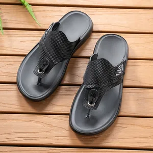 Detailansicht schwarzer Herren-Flip-Flops mit strukturierten Riemen auf Holzgrund.