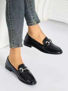 Mocasines negros clásicos con textura de cocodrilo y hebilla plateada lujo.