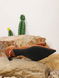 Detail view of brown crocodile-textured pumps with elegant bow and kitten heel.