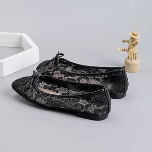 Detail showing the intricate floral lace mesh texture of black ballet flats.