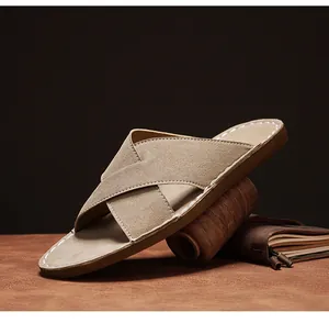 Gedetailleerd zicht op kaki suède herenslipper met kruisbanden en witte stiksels