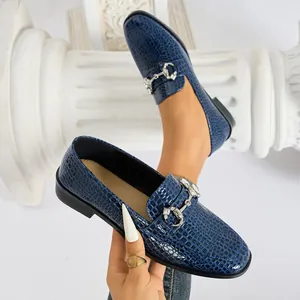 Mocasines azules elegantes para mujer con textura de cocodrilo y hebilla metálica.