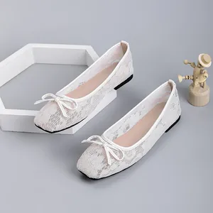 Detailed macro view of white floral lace mesh and elegant bow on square toe flats