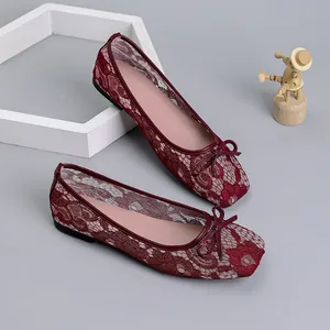 Macro view showing the intricate red lace mesh texture and bow detail of these flats