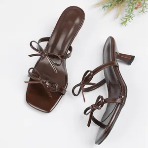 Elegantes sandalias marrón oscuro con punta cuadrada, lazos y tacones altos finos.
