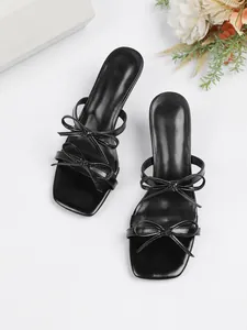 Detaillierte Nahaufnahme eleganter schwarzer High-Heel-Sandalen mit Schleifenverzierung