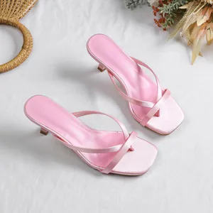 Detailed view of pink satin thong sandals with square toe and kitten heels on white cloth