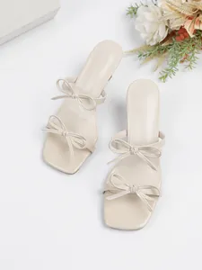Elegante beige Pantoletten mit quadratischer Spitze und feinen doppelten Schleifenriemen.