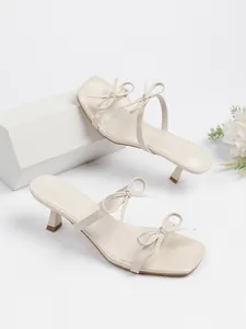 Detailansicht eleganter cremefarbener Sandalen mit quadratischer Zehe und modischen Schleifen