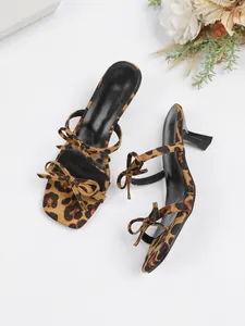 Vista detallada de los mules con estampado de leopardo, punta cuadrada y lazos decorativos.