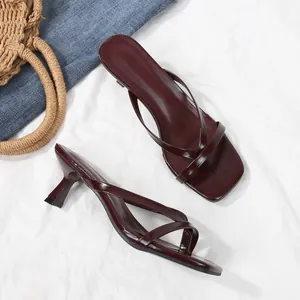 Elegant burgundy square toe thong sandals with slim kitten heels on white fabric background.