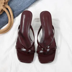 Top view close-up of elegant burgundy square toe thong heeled sandals on white fabric