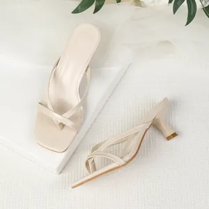 Close-up detail showing the square toe and thin kitten heel of beige thong sandals