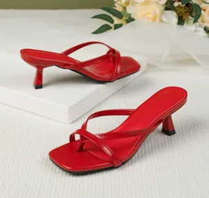 Elegant red kitten heel thong sandals with square toe and slim straps on white props