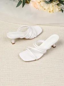Detailweergave van elegante witte sandaaltjes met bandjes en vierkante neus voor elke dag.
