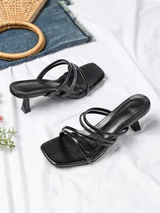 Gedetailleerd overzicht van elegante zwarte sandalen met smalle bandjes op een witte stof