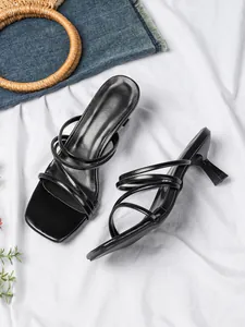 Detail van zwarte sandalen met vierkante neus en kitten hak met elegante bandjes