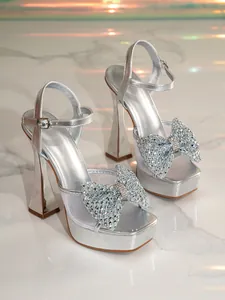 Elegant silver high-heeled sandals with sparkly rhinestone bow and mesh detailing.